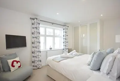 a white bedroom with a bed and a window at 5 The Sands in Polzeath