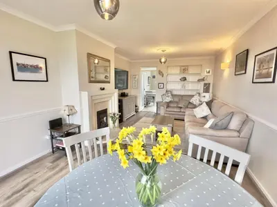 a living room with a table with yellow flowers on it at Curlews, 36 Egerton Road in Padstow