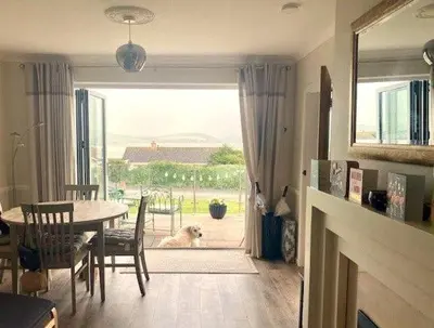 a living room with a table and a dog looking out the door at Curlews, 36 Egerton Road in Padstow