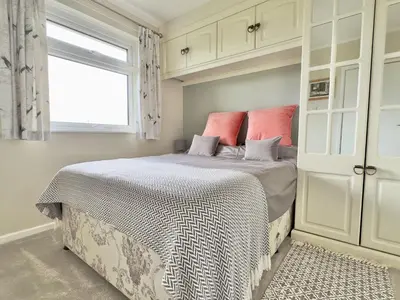 a bedroom with a bed with white cabinets and a window at Curlews, 36 Egerton Road in Padstow