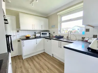 a kitchen with white cabinets and a sink and a window at Myebon in Padstow