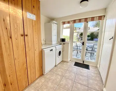 a kitchen with a white refrigerator and a washing machine at The Cottage in Padstow