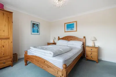 a bedroom with a wooden bed and a chandelier at Trenaton in Padstow
