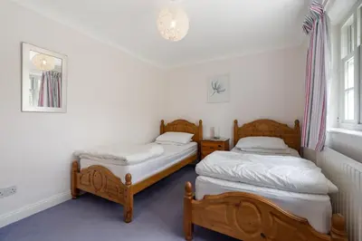 two twin beds in a room with white walls at Trenaton in Padstow