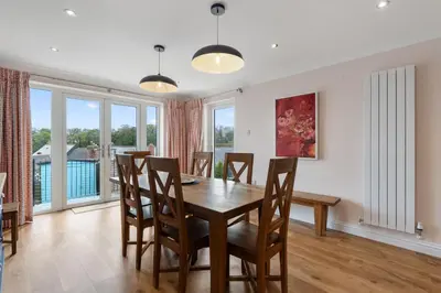 a dining room with a table and chairs and windows at Trenaton in Padstow