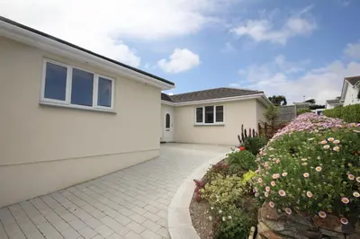 a white house with a driveway and flowers at 7 Porthilly View in Padstow