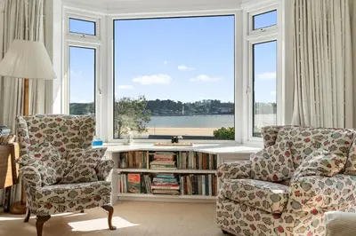 a living room with a couch and a chair and a window at Aeolian in Padstow