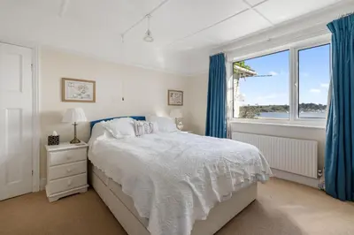 a white bedroom with a bed and a window at Aeolian in Padstow