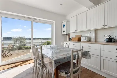 a kitchen with a table and chairs and a large window at Aeolian in Padstow