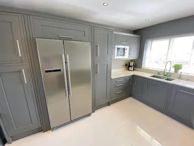 a kitchen with gray cabinets and a stainless steel refrigerator at Boskilly in St Merryn