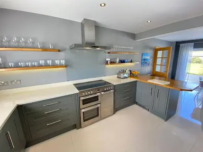 a kitchen with gray cabinets and a stove top oven at Boskilly in St Merryn