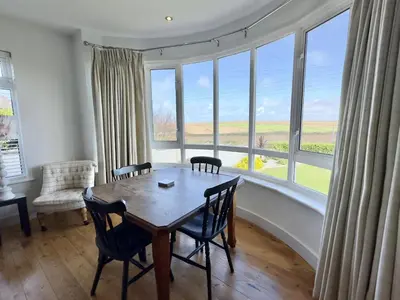 a dining room with a table and chairs and a large window at Hardown in St Merryn
