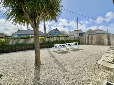 two white benches sitting next to a palm tree at Hardown in St Merryn