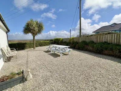 a white bench sitting on a gravel patio at Hardown in St Merryn