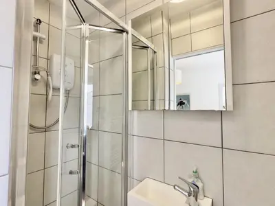 a bathroom with a shower and a sink and a mirror at Hardown in St Merryn