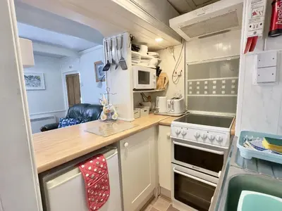 a small kitchen with a stove and microwave at Little Penty in Padstow