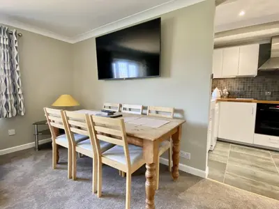 a dining room table with chairs and a television on the wall at Morwennol in St Merryn