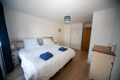 a bedroom with a large white bed with blue towels on it at Polcarrek in St Merryn