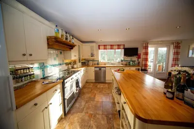 a kitchen with white cabinets and a wooden counter top at Polcarrek in St Merryn