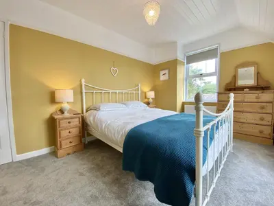 a bedroom with a white bed and a window at Treaaron in St Merryn