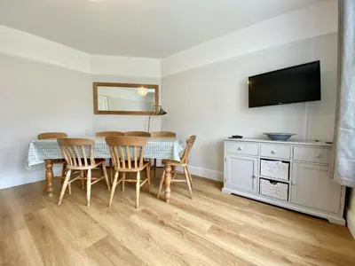 a dining room with a table and chairs and a television at Treaaron in St Merryn