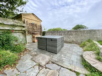 a stone patio with a black object in front of a wall at Treaaron in St Merryn