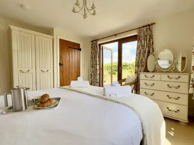a large white bed with a tray of bread on it at Wharf Cottage in Padstow