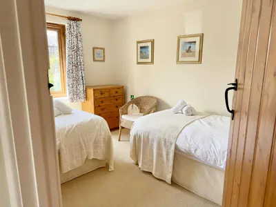 a bedroom with two beds and a dresser and a window at Wharf Cottage in Padstow