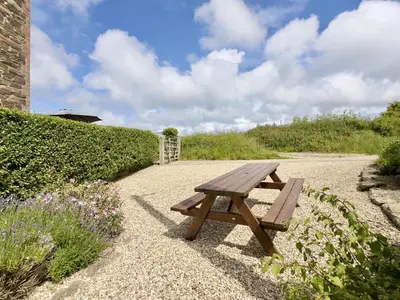 a wooden picnic table sitting on a gravel path at Wharf Cottage in Padstow