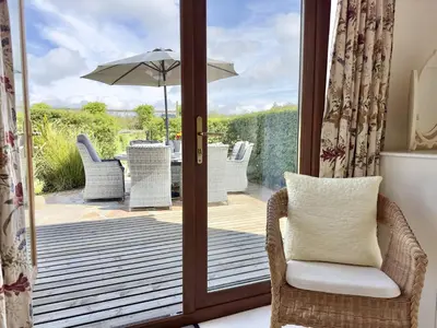 an open door to a patio with a chair and an umbrella at Wharf Cottage in Padstow
