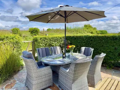 a table and chairs with an umbrella on a patio at Wharf Cottage in Padstow