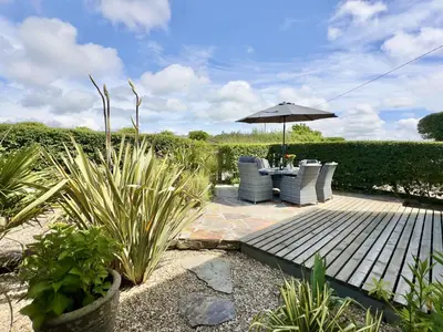 a patio with a table and chairs and an umbrella at Wharf Cottage in Padstow