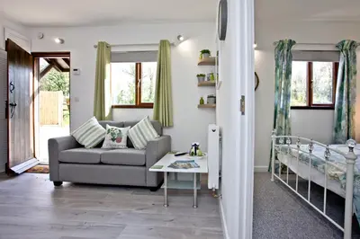 a living room with a couch and a bed at The Cabin at Hillhead farm in Saint Columb Major