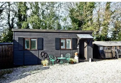a small cabin with a table and chairs in front of it at The Cabin at Hillhead farm in Saint Columb Major