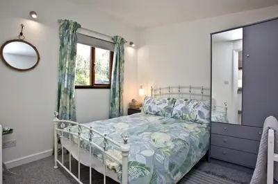 a bedroom with a bed and a mirror at The Cabin at Hillhead farm in Saint Columb Major