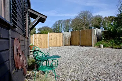 a green bench in a backyard with a fence at The Cabin at Hillhead farm in Saint Columb Major
