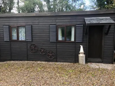 a small black cabin with windows and a door at The Cabin at Hillhead farm in Saint Columb Major