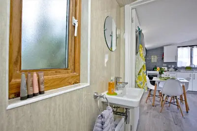 a bathroom with a sink and a window and a table at The Cabin at Hillhead farm in Saint Columb Major
