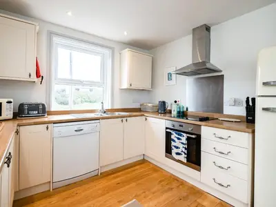 a kitchen with white cabinets and a stove top oven at The Lookout in Wadebridge