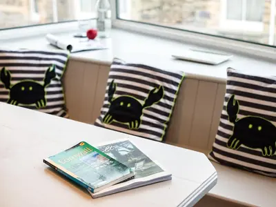 a book sitting on top of a table with pillows at The Lookout in Wadebridge