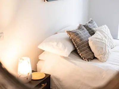 a bed with pillows and a lamp on a table at The Lookout in Wadebridge