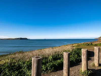 a fence on a beach with the ocean in the background at The Lookout in Wadebridge