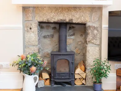 a stone fireplace with a stove in a house at St Ives View in St Ives