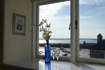 a blue vase with flowers and two wine glasses in a window at Grey Mullet Guest House in St Ives