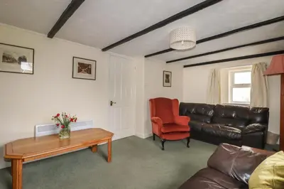 a living room with a leather couch and a table at Narnia in Delabole