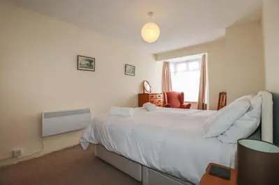 a bedroom with a large white bed and a chair at Narnia in Delabole