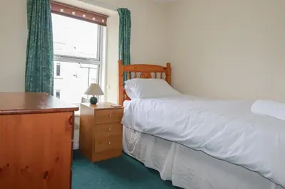 a bedroom with a bed and a dresser and a window at Narnia in Delabole
