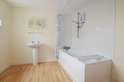 a white bathroom with a tub and a sink at Narnia in Delabole