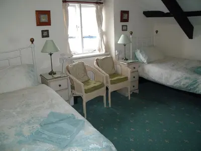 a bedroom with two beds and two chairs and a window at Grey Mullet Guest House in St Ives