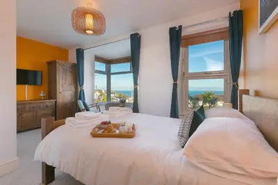 a bedroom with a large bed with a large window at Oystercatcher House in St Ives